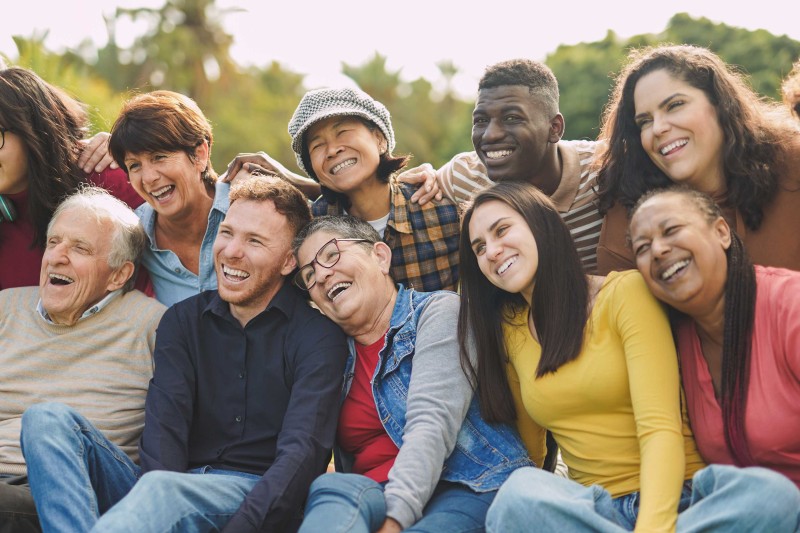 A group of older people sat outside laughing A group of older people sat outside laughing