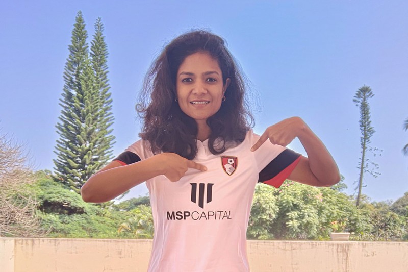 Aakanksha wearing an AFCB shirt, pointing to the club badge