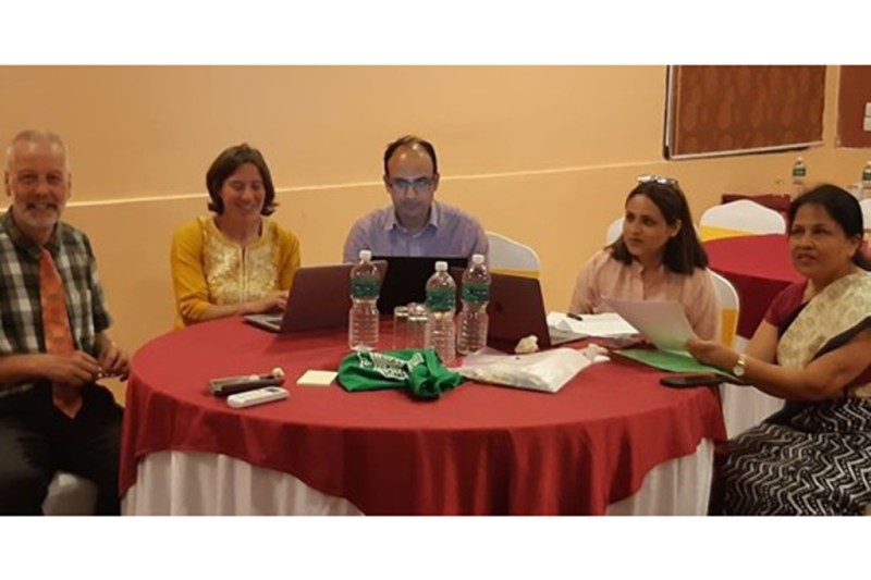 Two men and three women sitting around a table at the workshop, with laptop computers