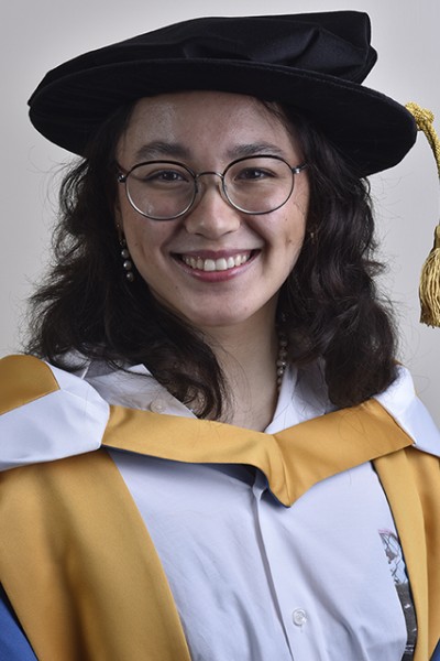 Alice Tai wearing her ceremonial graduation robes, looking at the camera smiling