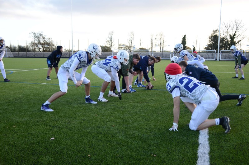 A group of men in american football kit, crouching down about to start play