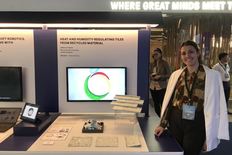 Angela stands next to a table containing sample roof tiles and some text explaining the product