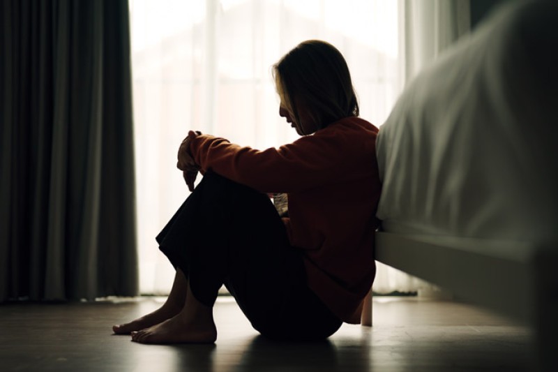 A silhouette of a young person, sitting in a crouch position looking like they are in despair