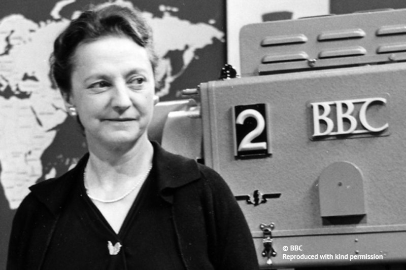 A black and white image of a woman in front of a BBC camera 