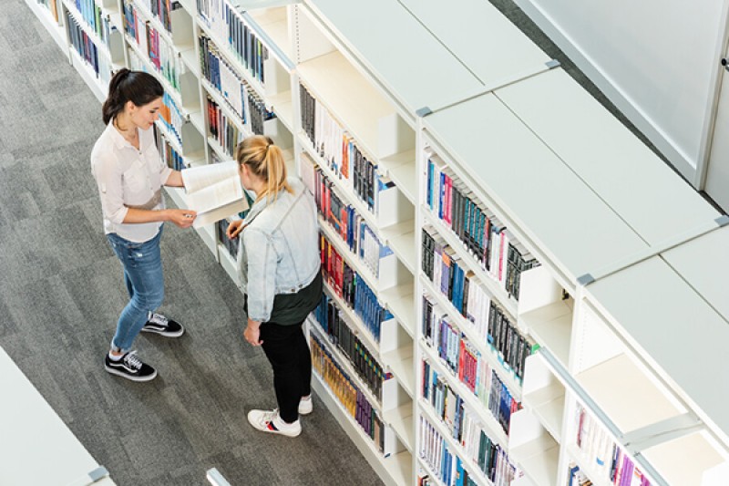 Students looking at books in Weston Library Students looking at books in Weston Library