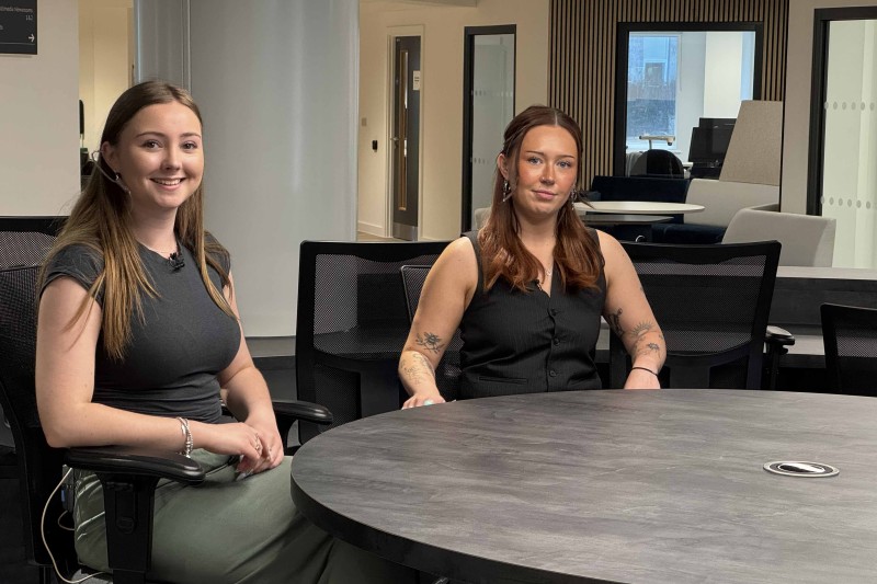 Two ladies sitting at a table, smiling at the camera