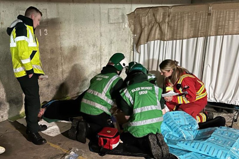 Paramedic students and directing staff treating a casualty Paramedic students gathered on the floor of the car park with directing staff treating a casualty