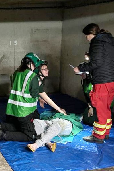 Paramedic students and directing staff treating a casualty Paramedic students gathered on the floor of the car park with directing staff treating a casualty