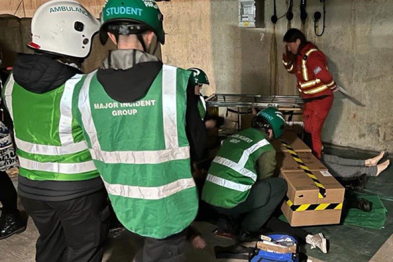 Paramedic students and directing staff treating a casualty Paramedic students gathered on the floor of the car park with directing staff treating a casualty