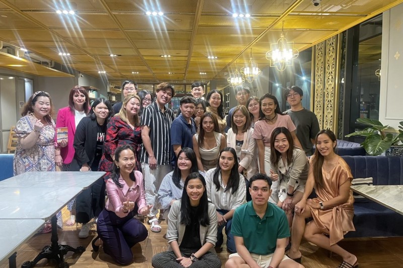 A group of around 25 people, some standing, some sitting, all looking at the camera smiling