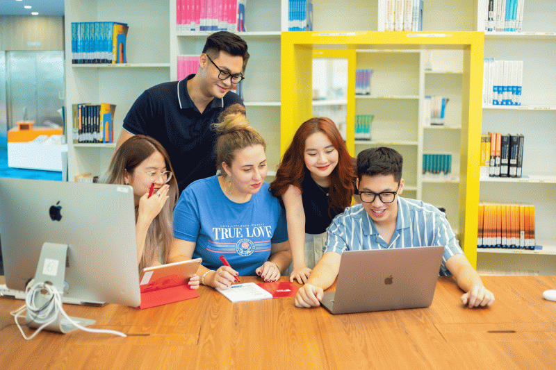 British University Vietnam students gathered around an iMac