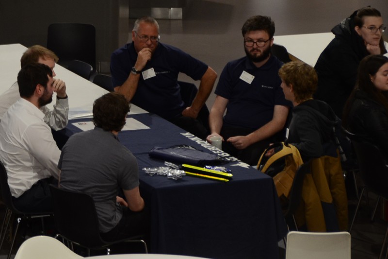 A group of students sitting around a table talking to staff from visiting companies