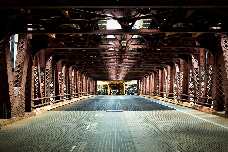 A view of a road running over a bride with large metal structures at the sides and at the top 