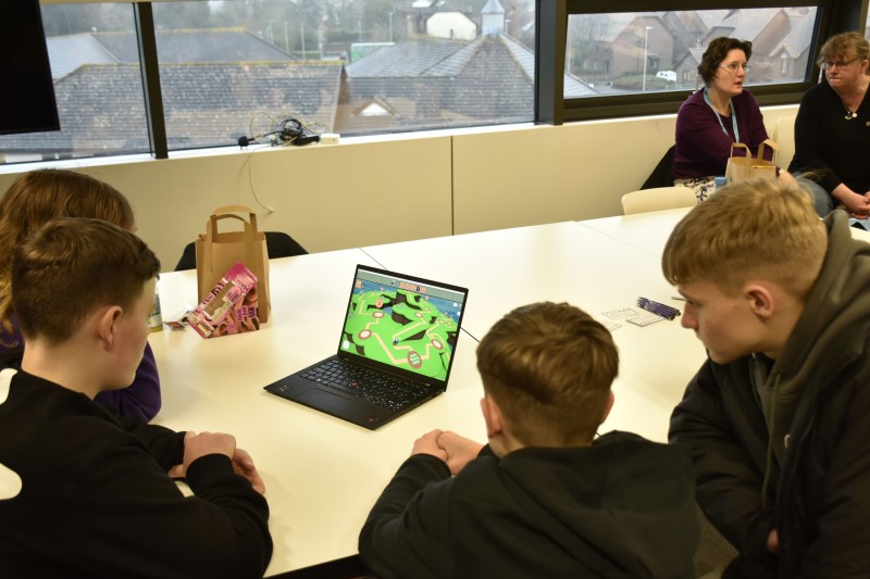 Four youngsters sitting in front of a laptop playing the Cygambit game