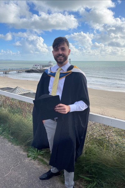 David Hicks, a Bournemouth University Lecturer in Politics, at his graduation with Bournemouth beach in the background.