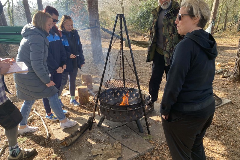 Students and staff standing around a fire