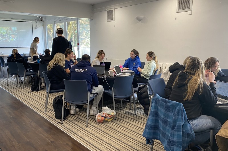 Groups of students sitting around large tables studying