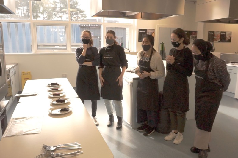 Students in the kitchen looking at chocolate cakes 