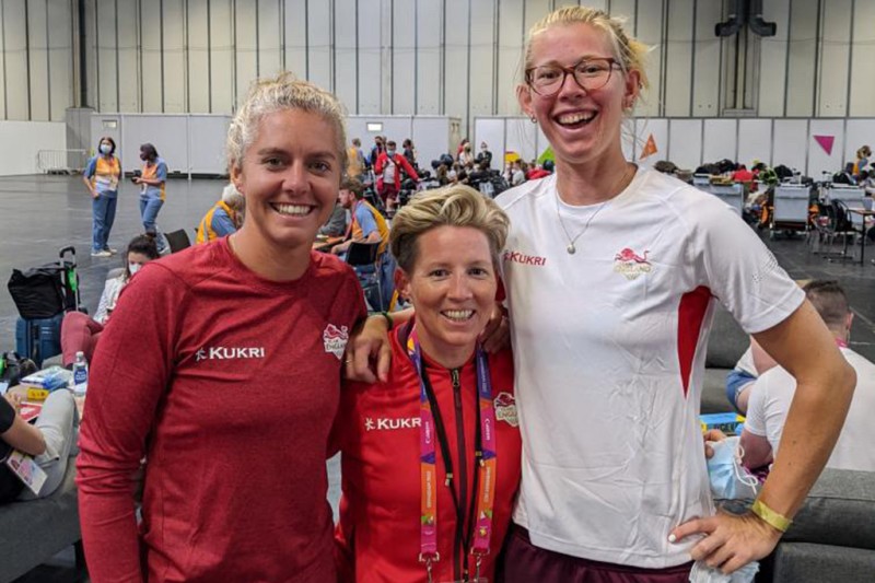 Emma Kavanagh in Team England's welcome centre standing alongside beach volleyball players Jess Grimson on the left and Daisy Mumby on the right
