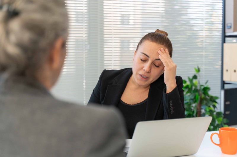 A woman looking very tired trying to talk to another woman