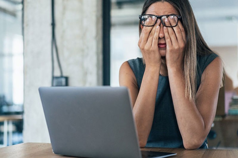 Lady sitting at her desk rubbing her eyes