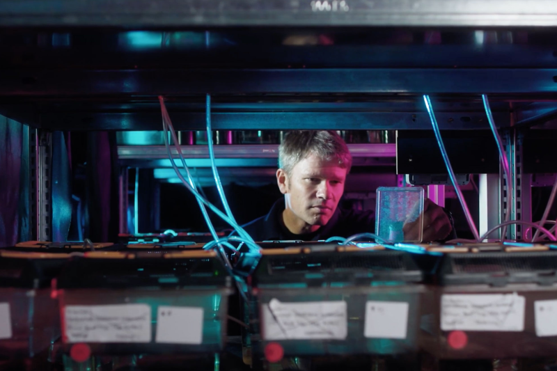 Professor Robert Britton peers through shelves containing fish tanks 