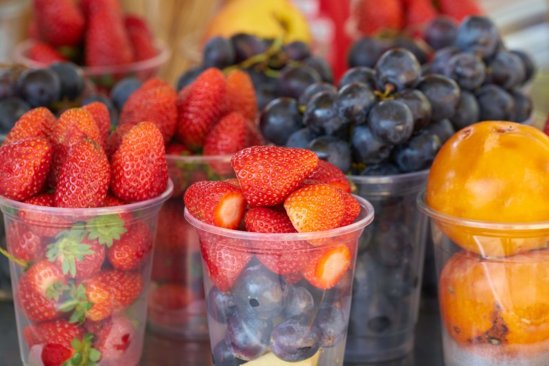 Plastic cups full of strawberries and blueberries