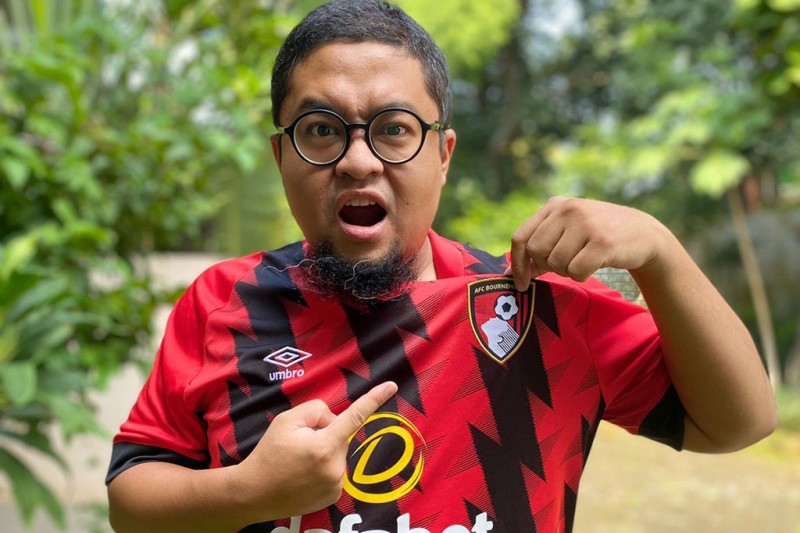 Fuddy looking at the camera, wearing an AFCB shirt pointing at the AFCB badge