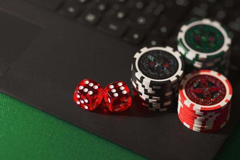 two dice and two piles of gambling chips on a computer keyboard