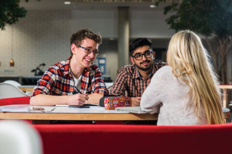 Three students sitting around a table talking and studying