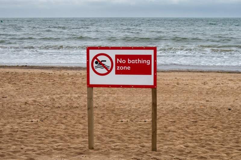 A sign on a beach, warning people not to swim.
