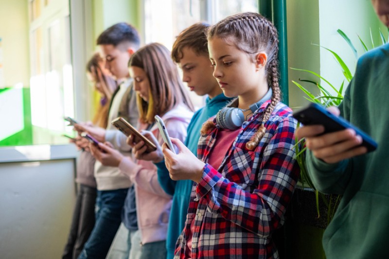 A line of children all on their mobile phones 