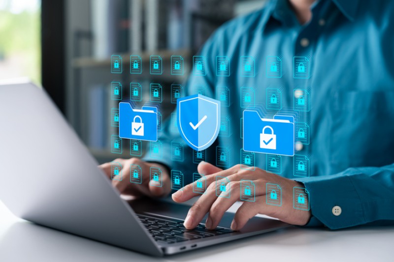 Cybersecurity concept with businessman using a laptop to protect data folders and digital files.