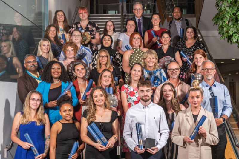 Several rows of people in a group photo. The people on the front row hold their awards