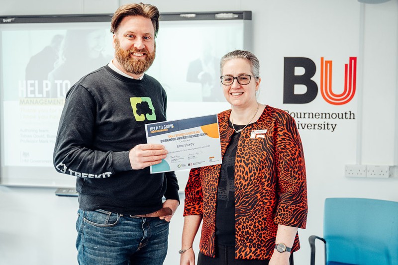 A man from Tree Kit holding a certificate from the Help To Grow course, standing next to a lady, both looking at the camera smiling