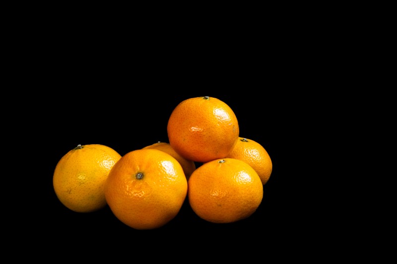 A photograph of a group of tangerines on black cloth