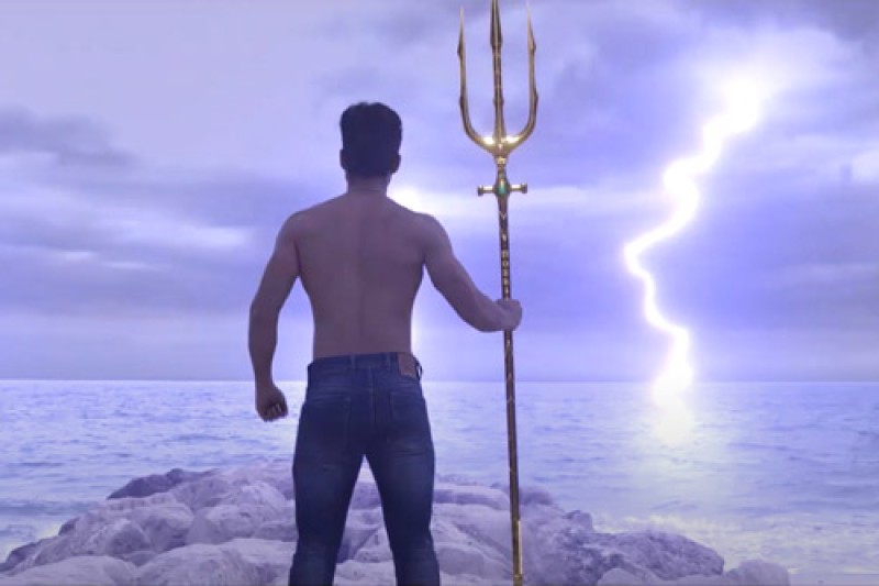 Computer animation showing the back of a man holding a trident, looking out to sea with a striking in the background