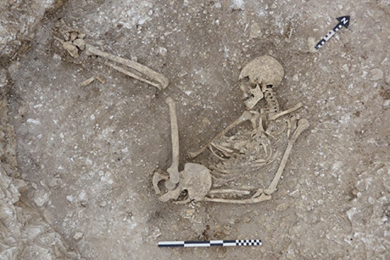 A human skeleton in an oval pit