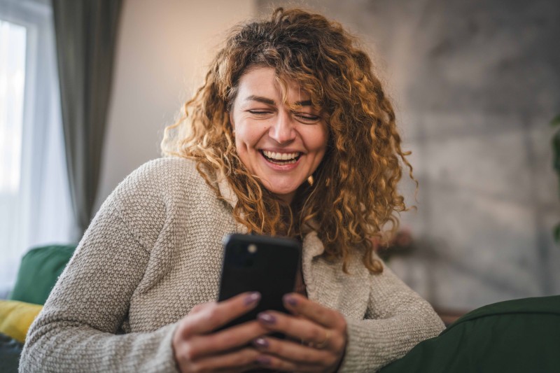 A woman looking at her phone screen and smiling