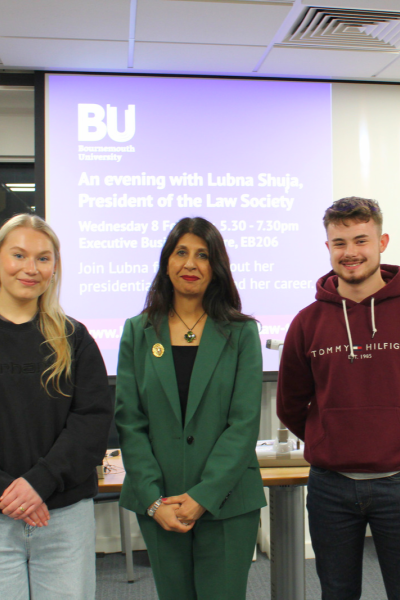 Lubna Shuja looking at the camera with a female student to her right and male student to her left