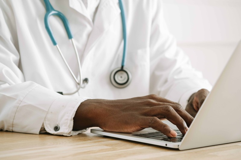 A doctor typing on a laptop