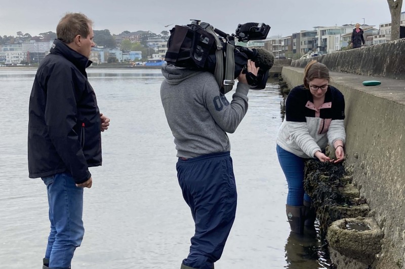 Jess being filmed by aa TV camera exploring a rockpool 