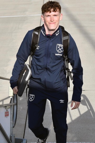 Joseph Evans walking up some steps, smiling at the camera, wearing a West Ham United tracksuit