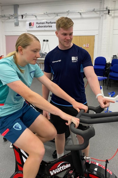 BU student Kieran Keleher and player on exercise bike BU student Kieran Keleher and player on exercise bike