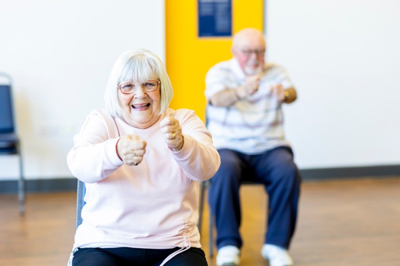 An older adult taking part in chair aerobics