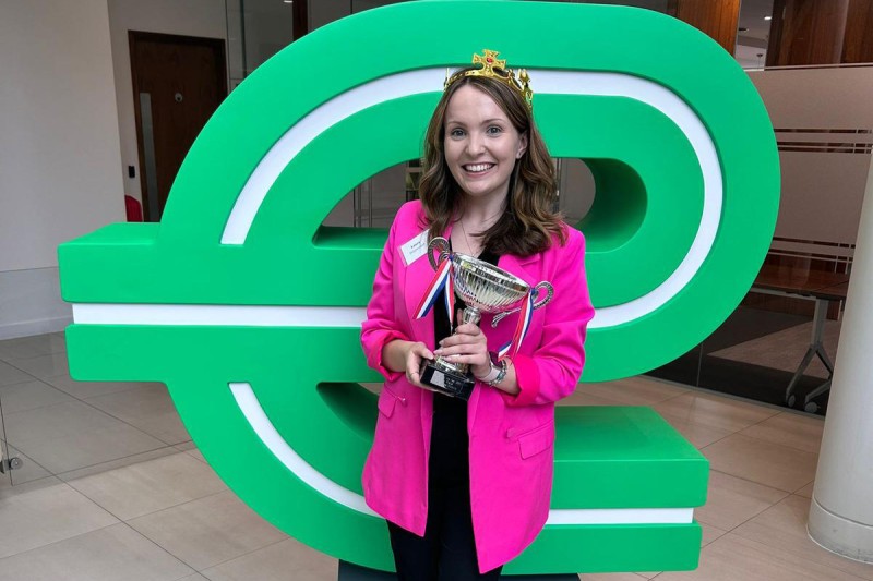 Laura holding her award standing in front of the Enterprise logo