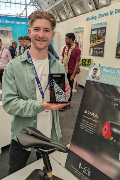 Marcus holding up his award with a bicycle saddle in front of him