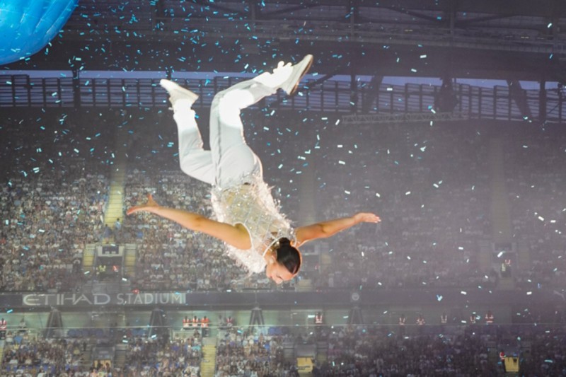 Millie in the air during a trampoline routine. A large stadium crowd in the background