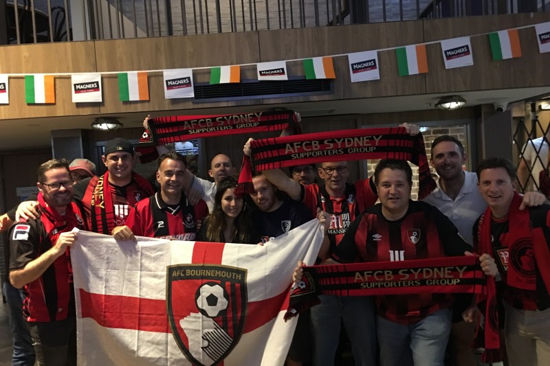 Nick and AFCB Sydney supporters A large crowd of people holding up an England flag with the AFCB badge in the middle