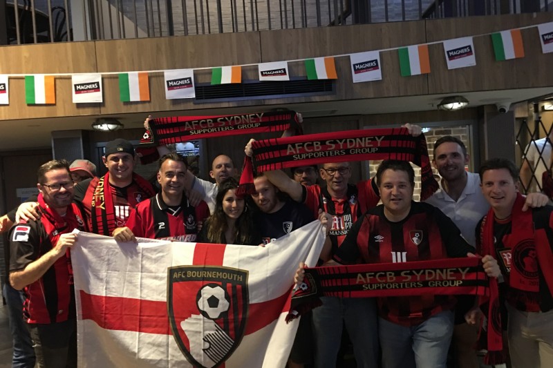 A large crowd of people holding up an England flag with the AFCB badge in the middle